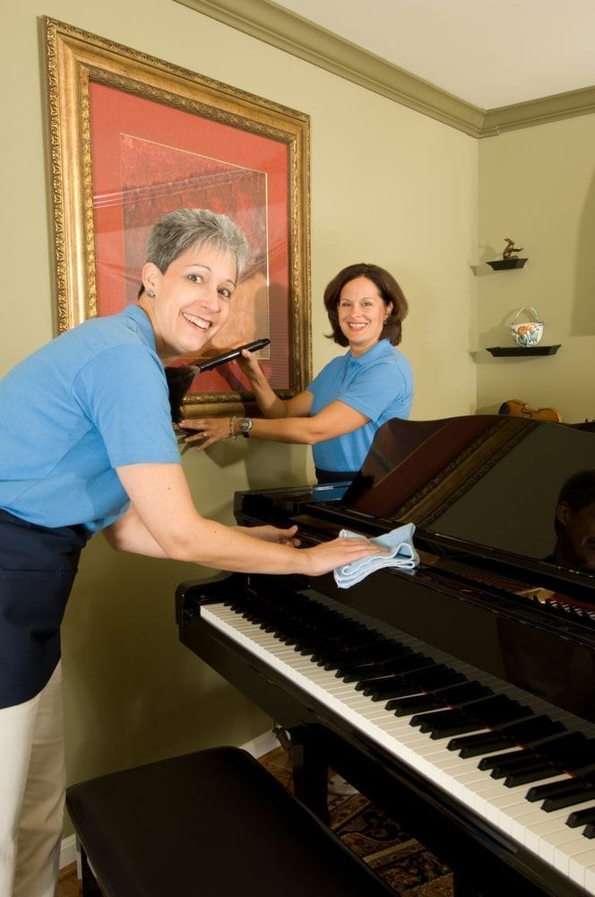 Ladies cleaning a piano and picture