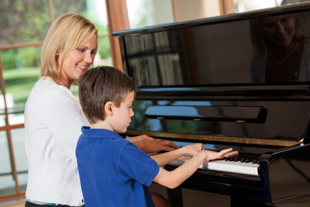 Lady teaching young boy piano