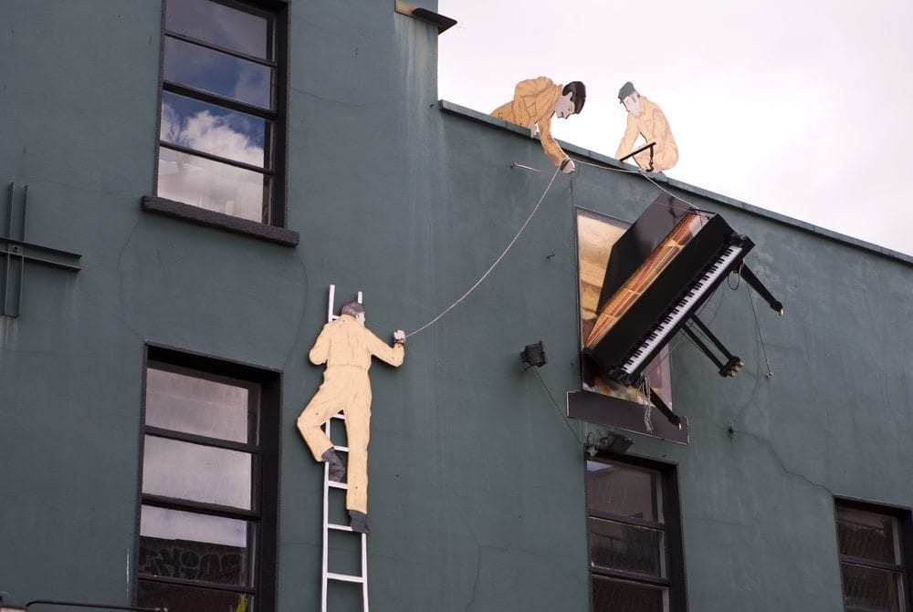 Three men moving a piano from an apartment