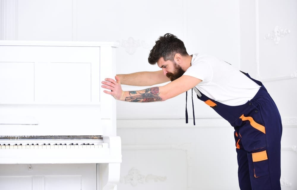 Worker in overalls pushes piano