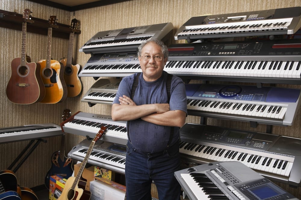 Male music store owner standing arms crossed