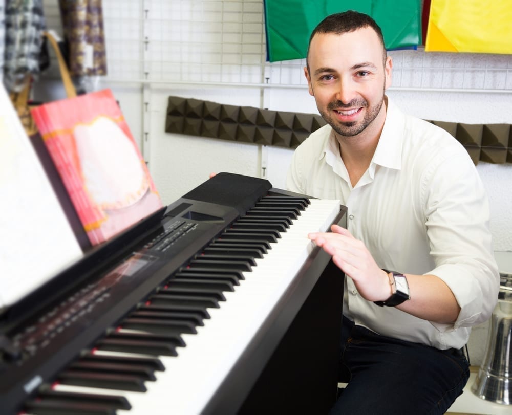 Young customer buying synthesizer in music shop