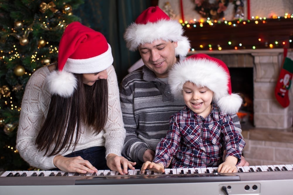 Family wearing Santa hats and playing the piano