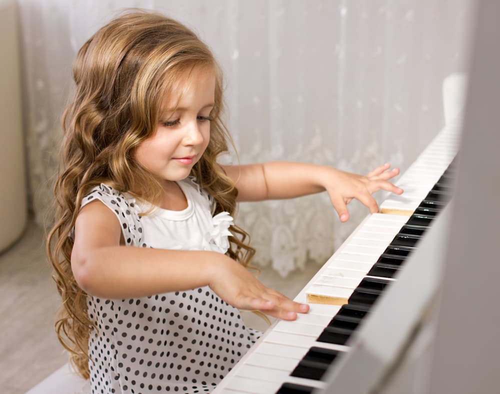 beautiful little girl playing piano in light room
