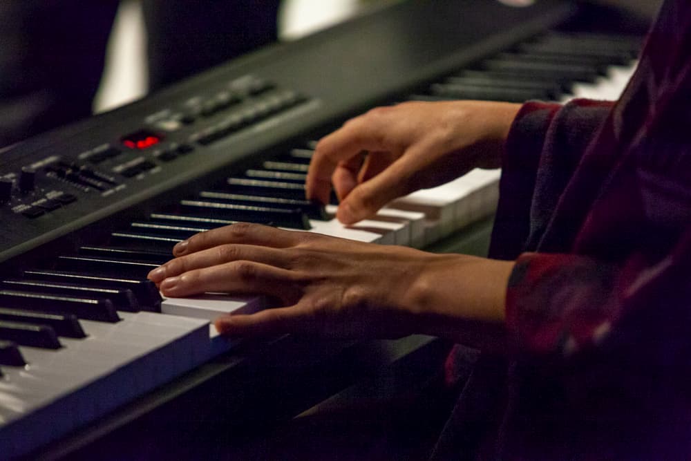 Young woman is playing digital piano in a pub - Closeup picture shot live during a concert