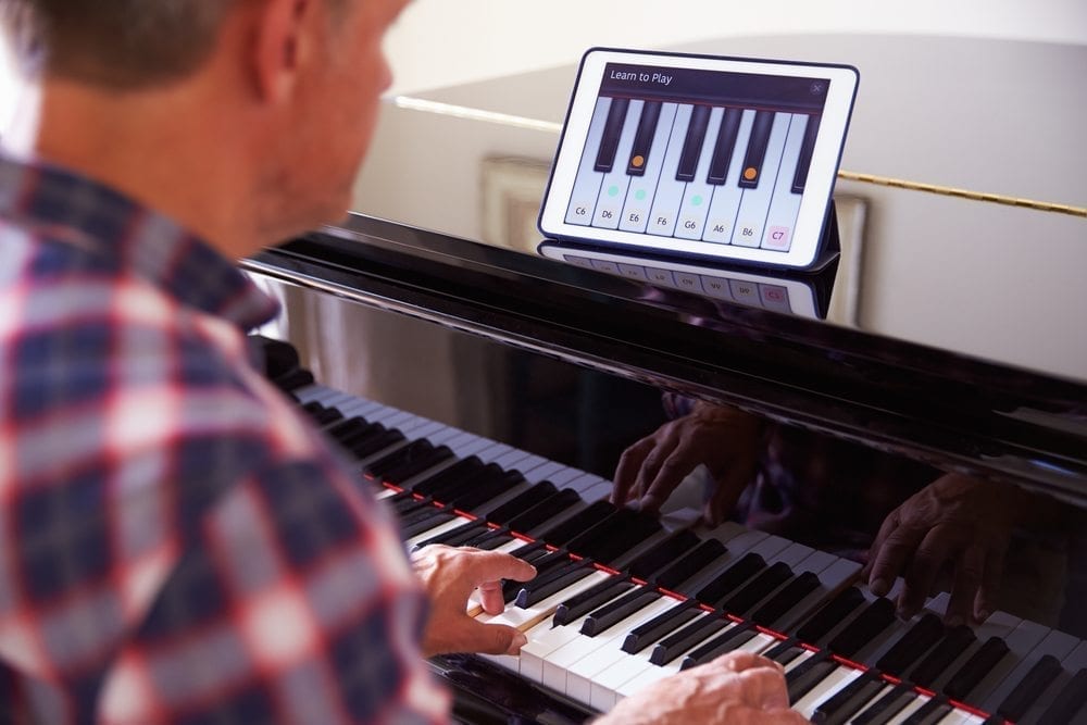 Man learning to play piano using digital app